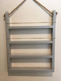 a wooden shelf with rope hanging from it's sides on the wall next to a white wall