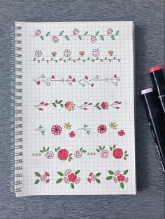 a notebook with flowers on it next to two pens