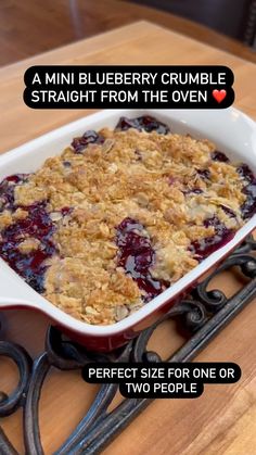 a casserole dish filled with blueberry crumbles on top of a wooden table