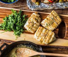 some fish and vegetables are on a cutting board next to a skillet with broccoli