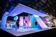 an exhibit booth at a trade show with people standing in front of it and lights on the walls