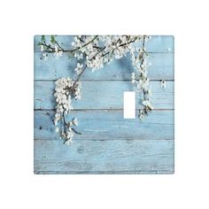 a light switch plate cover with white flowers on blue wood planks and a branch