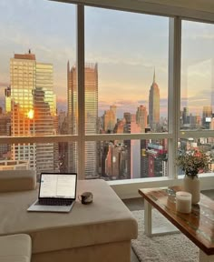 a living room filled with furniture and a view of the city at sunset or dawn