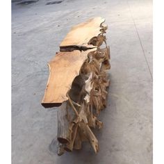 a wooden bench made out of logs and branches on concrete flooring with cement area in the background