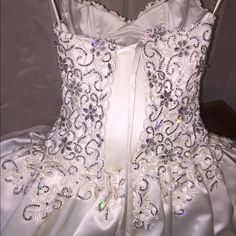 the back of a wedding dress with beading and flowers on it's skirt