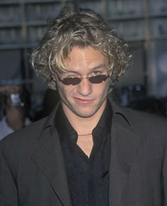 a man with curly hair and sunglasses looking at his cell phone