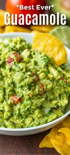 guacamole in a white bowl with tortilla chips on the side