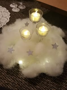 three candles are lit on top of some fluffy white material with silver stars in the middle