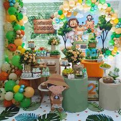 a table filled with balloons and decorations for an animal themed birthday party or baby shower