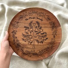 a hand holding a wooden plate with a family tree engraved on the front and sides