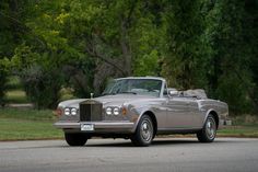 an old car is parked on the side of the road in front of some trees