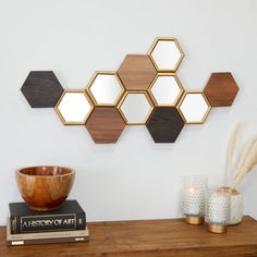 a wooden table topped with a bowl next to a wall mounted mirror on top of it