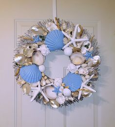 a wreath with shells and seashells hanging on a door