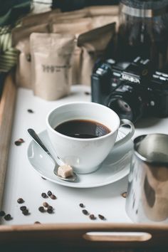 a cup of coffee sitting on top of a white saucer next to a camera