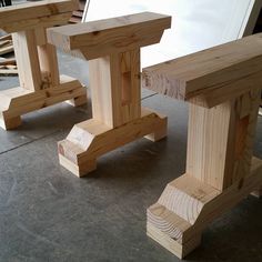 two wooden benches sitting next to each other on top of a cement floor in front of a white board