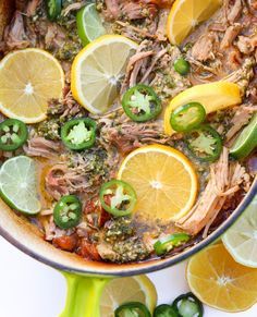 a pot filled with meat and vegetables next to sliced lemons