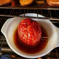 a bowl filled with liquid sitting on top of an oven rack next to muffins