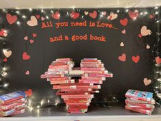 books are stacked on top of each other in front of a sign that says, all you need is love and a good book