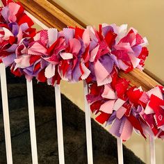 red, pink and purple paper flowers are on the banister