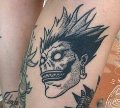 a close up of a person's leg with tattoos on it and an image of a demon