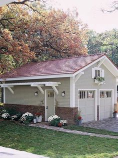 a small gray garage with white trim on the roof and two windows in front of it