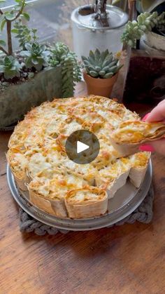 a person holding a piece of food in front of a cake on a plate with succulents