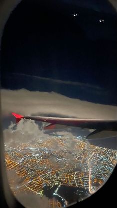 an airplane wing is seen through the window of another plane's engine as it flies over a city at night