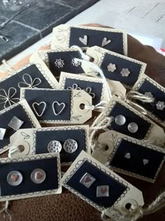 small black and white tags with hearts on them sitting on a brown table next to some string