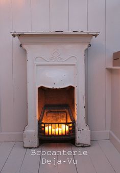 an old fireplace with lit candles in the middle and white paint on the wall behind it