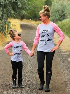 two women walking down a dirt road with one holding the hand of another woman's hand