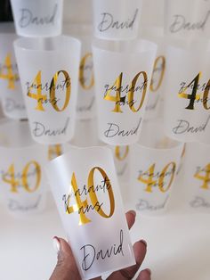 a person holding up a card with the number forty and 40 on it in front of a group of cups