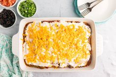 a casserole dish with cheese and other toppings on the side next to bowls of beans