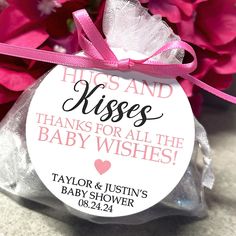 a baby shower gift bag with pink flowers in the background and kisses for all the baby wishes on it