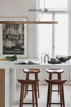 two wooden stools sitting in front of a white counter top next to a window