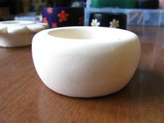 a white bowl sitting on top of a wooden table next to other bowls and cups