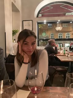 a woman sitting at a table with wine glasses