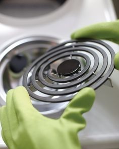 a person in green gloves is holding a stove burner