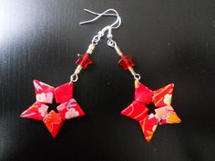 two red and yellow stars hanging from silver earwires on a black table top