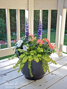 a potted plant sitting on top of a wooden table next to a porch railing