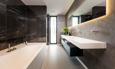 a bathroom with black marble walls and flooring, along with a white bathtub