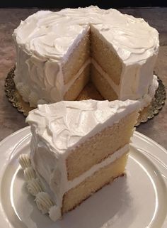 a white cake sitting on top of a plate next to a slice cut out of it