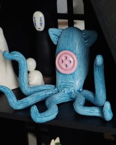 a blue figurine sitting on top of a black shelf next to other items