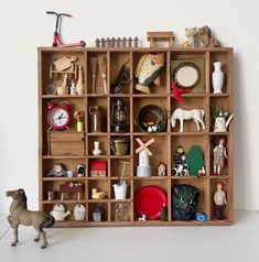 a toy horse is standing in front of a wooden shelf filled with figurines