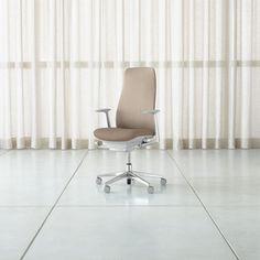 an office chair sitting on top of a white tile floor next to a curtained window