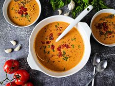 two bowls of soup with spoons and tomatoes