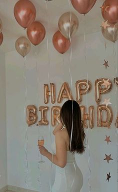 a woman standing in front of balloons with the words happy birthday on it