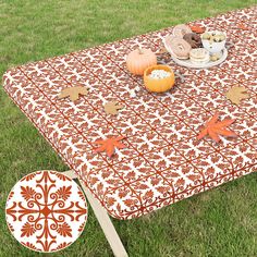 an orange and white table cloth with pumpkins on it in the middle of grass