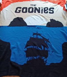 the goonies t - shirt is laying on top of a table