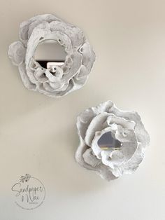 two white flower shaped mirrors mounted to the side of a wall next to each other