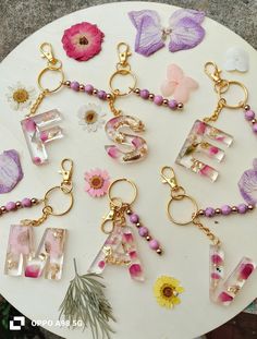 many different types of letters and flowers on a white table with gold keychains